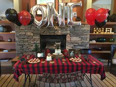 a table topped with cake and balloons in front of a fireplace