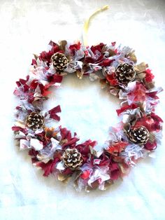 a wreath with pine cones and red flowers on white paper toweled tablecloth, ready to be used as decoration