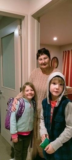 a woman and two children standing in front of a door