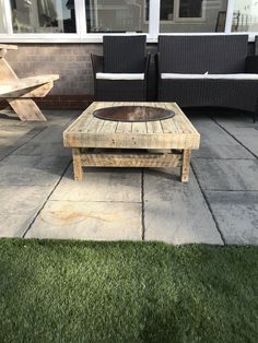 a wooden coffee table sitting on top of a stone patio next to black wicker chairs