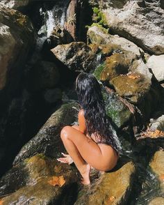 a woman is sitting on rocks in the water