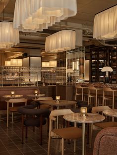 an empty restaurant with tables and chairs in the center, lights hanging from the ceiling