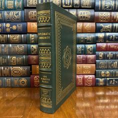 a stack of books sitting on top of a wooden table next to a pile of other books