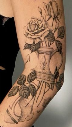 a woman's arm with roses and an old fashioned vase tattoo on her left arm