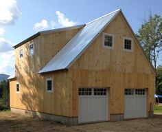 a two story garage with three windows and a metal roof on the side of it