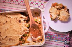 a casserole dish with meat and vegetables in it next to a white plate