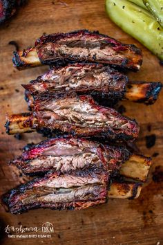 barbecue ribs on a wooden cutting board with pickles and seasoning next to it