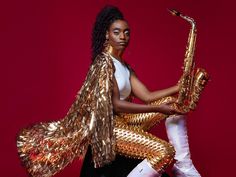 two women dressed in gold and white, one holding a saxophone while the other holds her leg