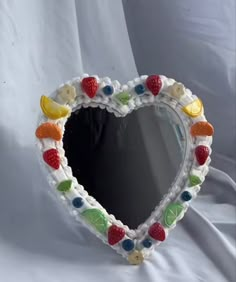 a crocheted heart shaped mirror with fruit on it