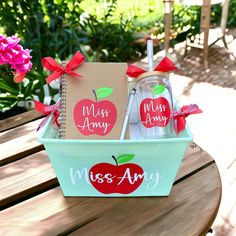 an apple themed teacher's day gift set in a blue basket on a wooden table