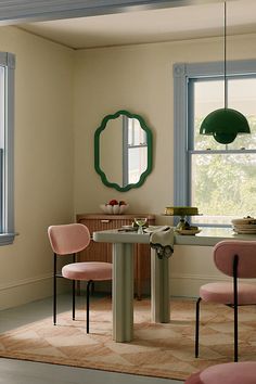 a dining room with pink chairs and a round table