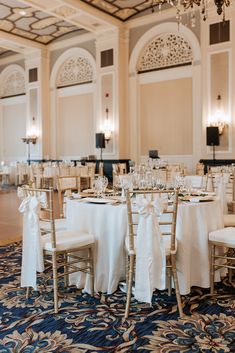 the tables are set with white linens and gold chairs for an elegant wedding reception