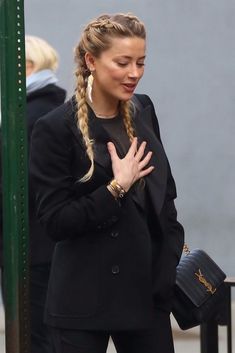 a woman in black jacket and pants holding her hands together