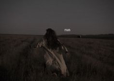 a woman walking through a field with the words run in front of her on it