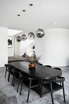 a dining room table with chairs and hanging lights