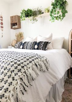 a white bed topped with lots of pillows next to a plant filled wall mounted above it