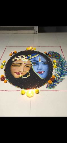 a decorated floor with two faces on it and candles in front of the face, surrounded by feathers