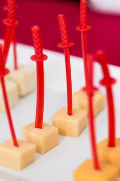 several pieces of cheese with red sticks sticking out of them on a white tablecloth