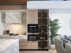 a modern kitchen with marble counter tops and wooden cabinetry, along with white chairs