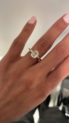 a woman's hand with a diamond ring on top of her finger and the other hand holding an engagement ring