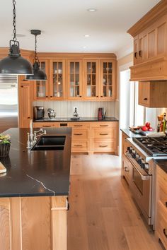 a large kitchen with wooden cabinets and black counter tops, along with stainless steel appliances