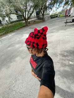 a woman wearing a red and black crochet hat on top of her head