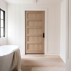 a bathroom with a bathtub, rug and wooden door in the middle of it