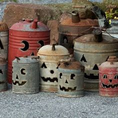 old metal canisters with faces painted on them sitting in front of a rock wall