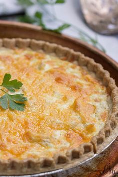 a quiche with cheese and parsley in a pie pan on a table top