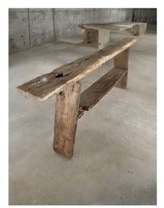 two wooden benches in an empty room with concrete flooring and cement walls behind them