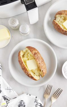 two white plates with bread and cheese on them next to silver utensils, salt and pepper shakers