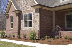 a brick house with landscaping around the front door and windows on either side of it