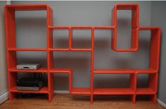 an orange book shelf sitting on top of a hard wood floor next to a wall