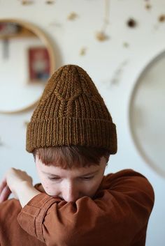 a young boy wearing a knitted brown hat