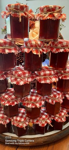 several jars of jam are stacked on top of each other with red and white gingham cloth