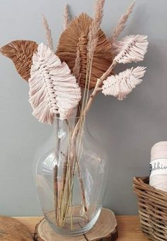 dried flowers in a glass vase on a wooden table next to a yarn ball and twine