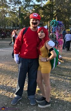 a man standing next to a woman in a yellow dress and red hat at an amusement park