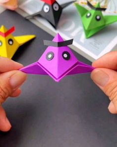 two hands holding origami birds on a table