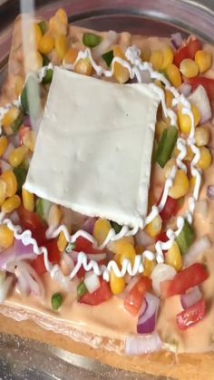 a square shaped pizza topped with corn, cheese and onions on top of a glass plate