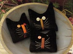 three black cats are sitting in a bowl with buttons on their faces and eyes,