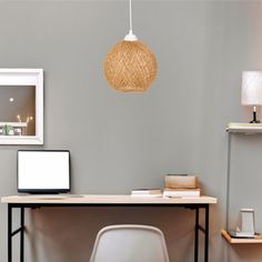 a desk with a laptop, lamp and pictures on the wall