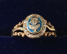 an antique ring with blue and white stones in the center on a black velvet surface