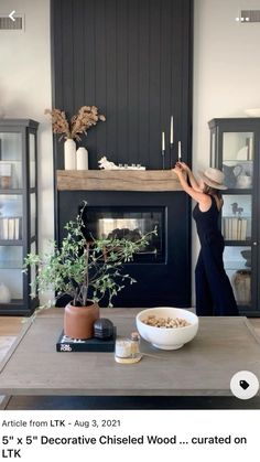 a woman standing in front of a fireplace with a bowl of food on the table