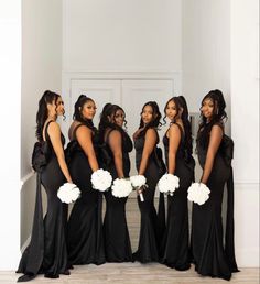 a group of women in black dresses standing next to each other and holding bouquets