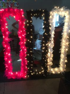 two large mirrors decorated with lights and feather trimmings, one in red and the other in white