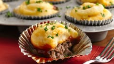 a muffin tin filled with meat and cheese cupcakes next to a fork