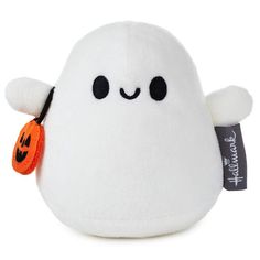 a white stuffed animal with black eyes and a pumpkin on it's ear,