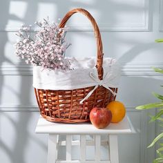 a wicker basket with flowers and fruit on a table