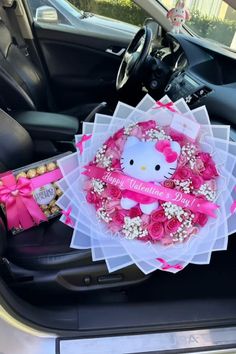 hello kitty wreath in the back seat of a car with pink roses and baby's breath