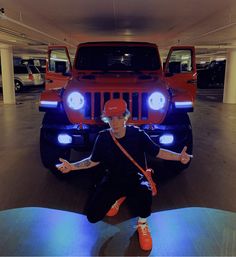 a man sitting in front of a red jeep